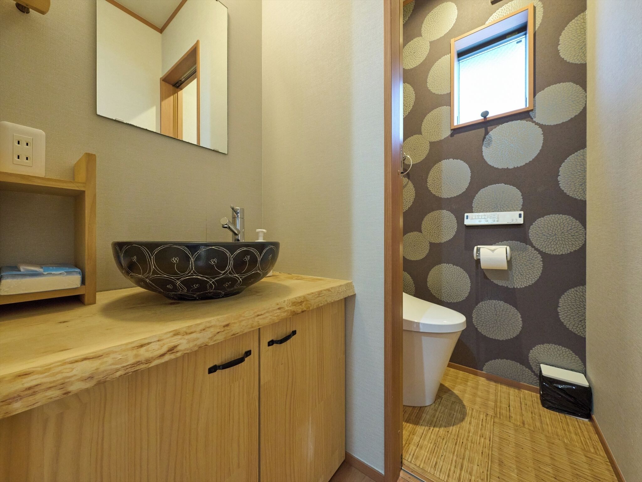 Ein Badezimmer mit einem Holzkosmetikschrank, einem großen dekorativen Waschbecken, einem Spiegel, einer Toilette und einem am Wand montierten Fernseher.