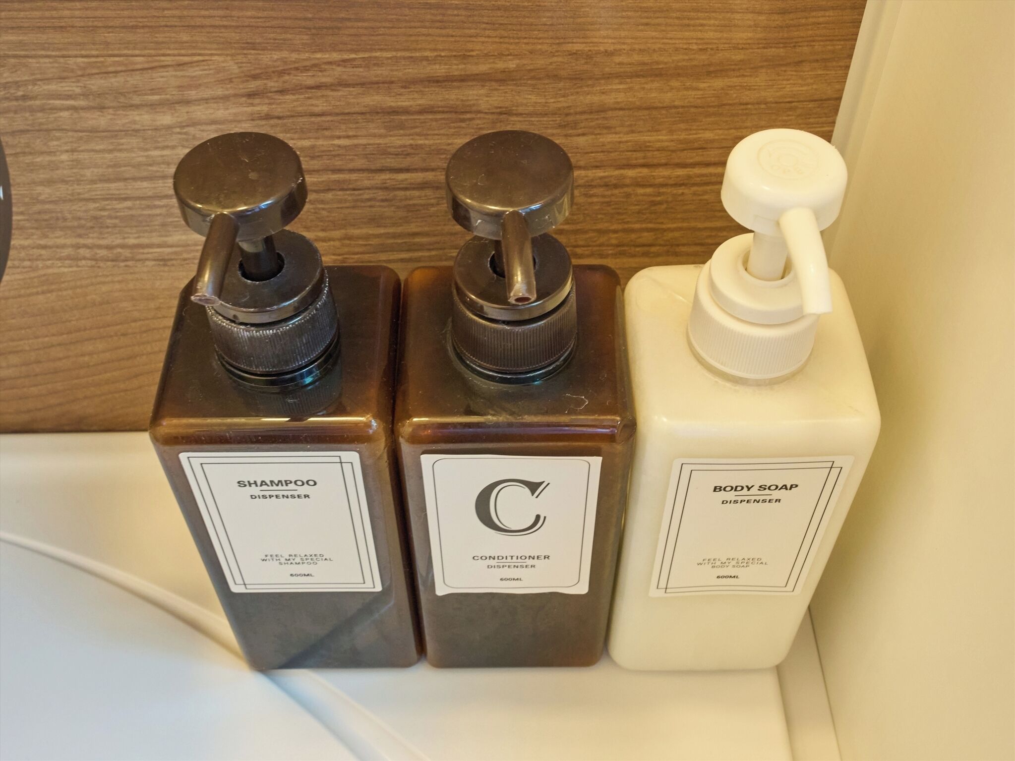 Three bottles of shampoo and body soap on a white surface.
