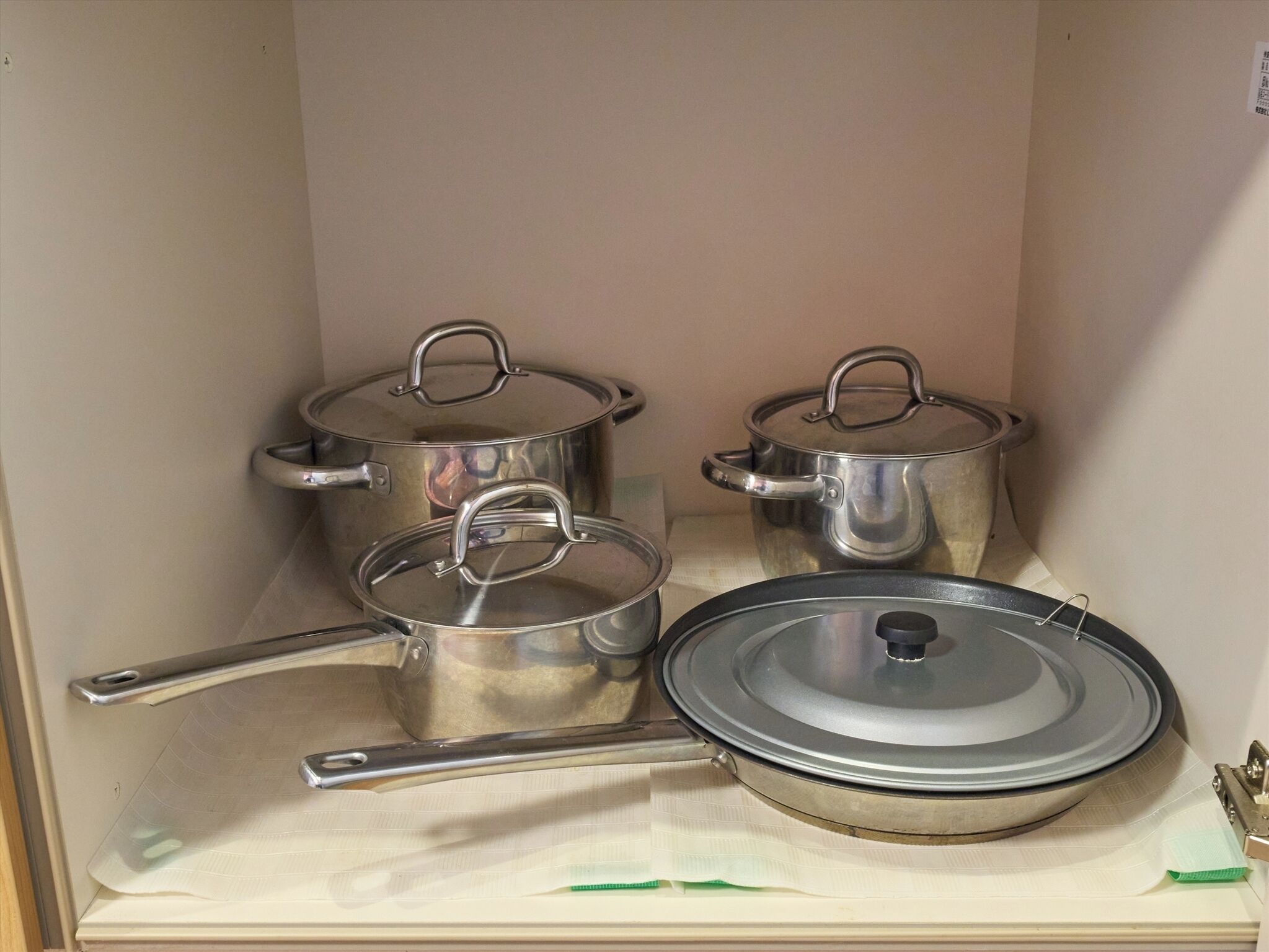 Una cocina con ollas y sartenes de acero inoxidable, una sartén y una estufa.