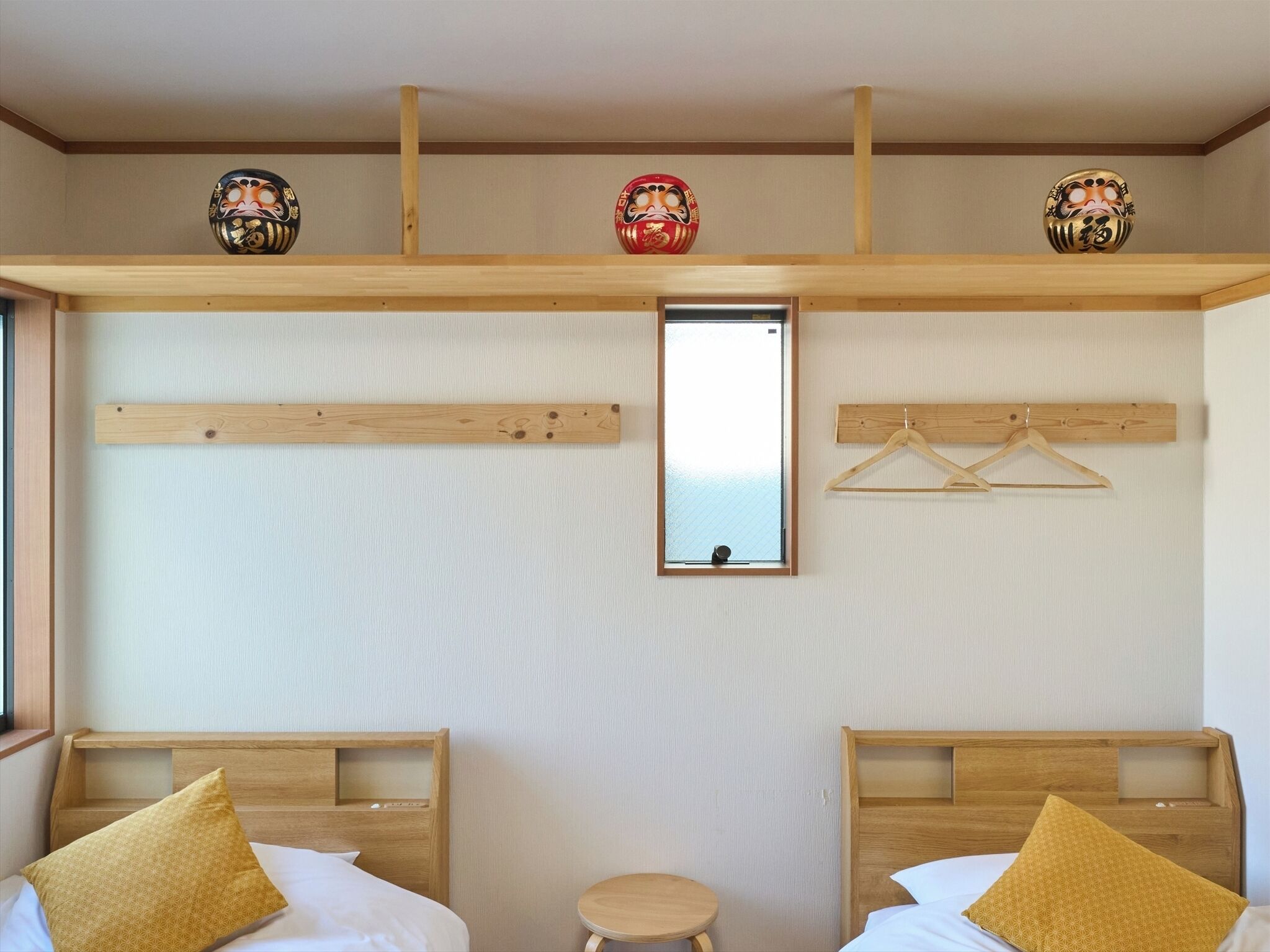 A hotel room with two beds, a small table, a mirror, and wooden beams on the ceiling.