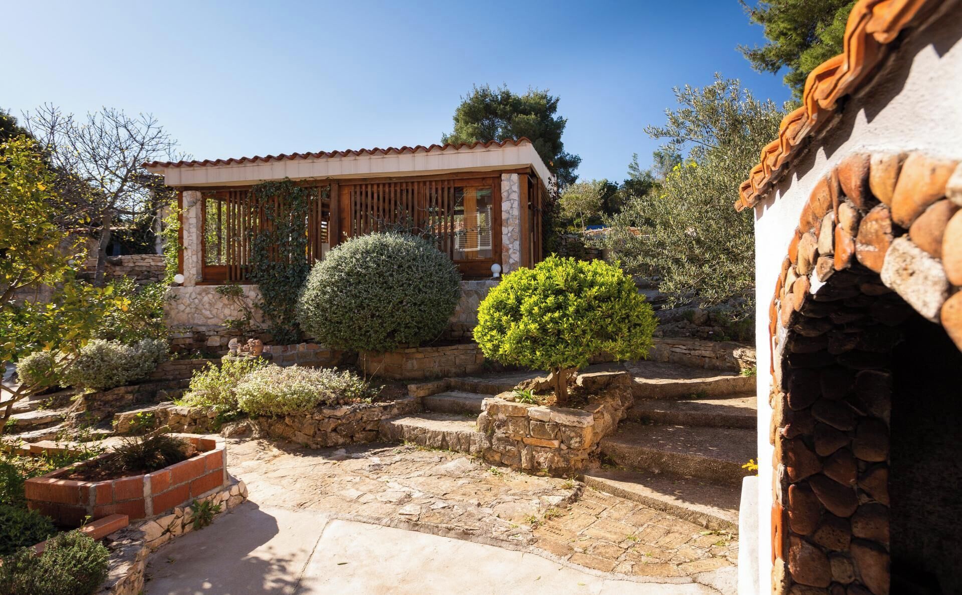 A traditional stone building with a tiled roof, surrounded by well-maintained gardens and stone pathways.