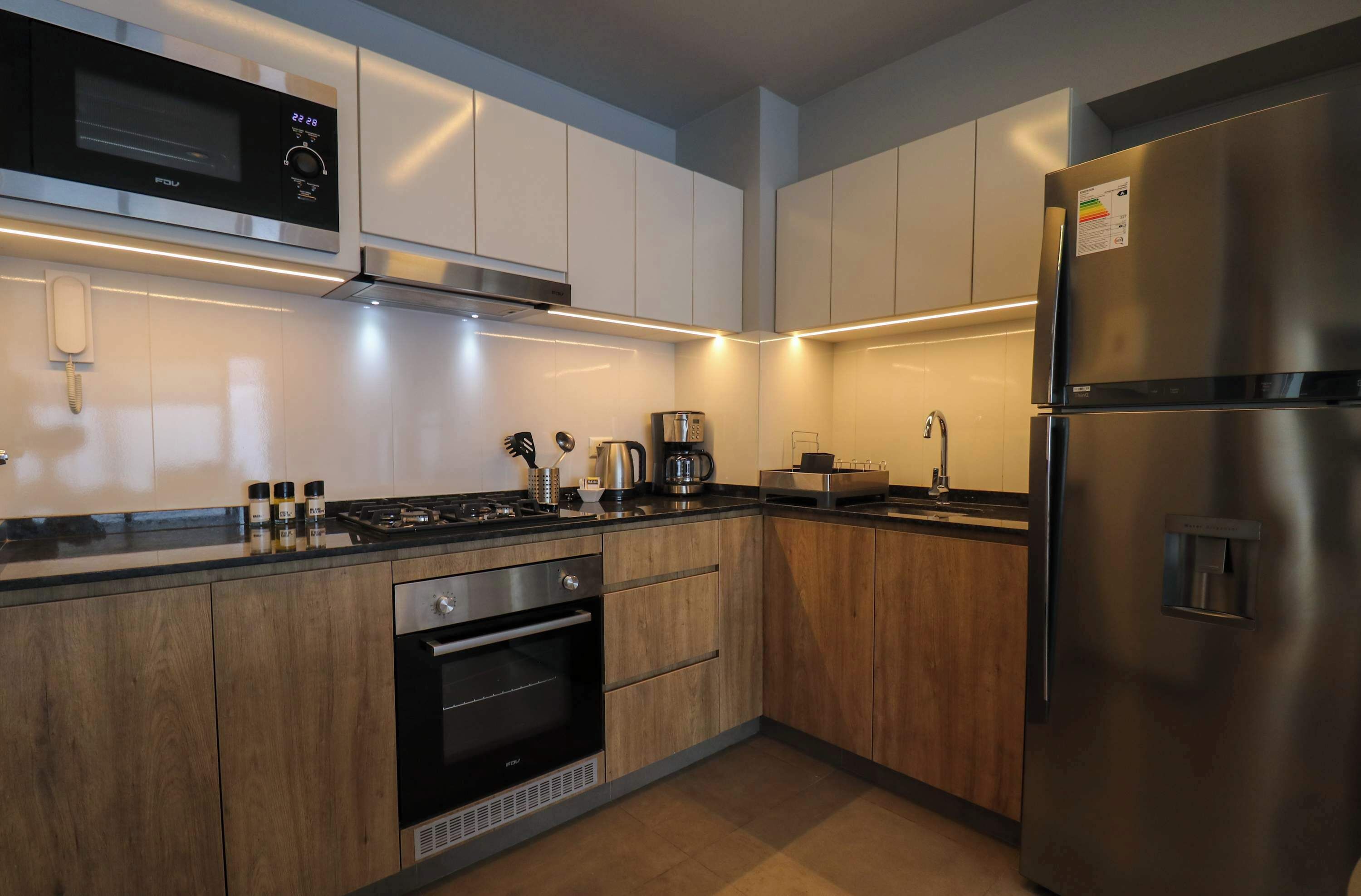 A modern kitchen with stainless steel appliances, wooden cabinets, and under-cabinet lighting.