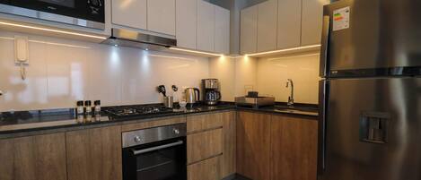 A modern kitchen with stainless steel appliances, wooden cabinets, and under-cabinet lighting.