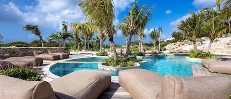 A pool area with lounge chairs and palm trees.
