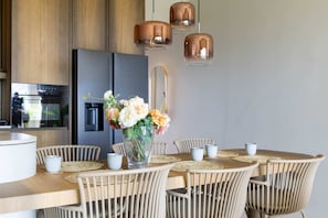 A modern kitchen with a wooden dining table, chairs, and a vase of flowers. - The Reef Superior Penthouse With Ocean View (Sint Michiel)