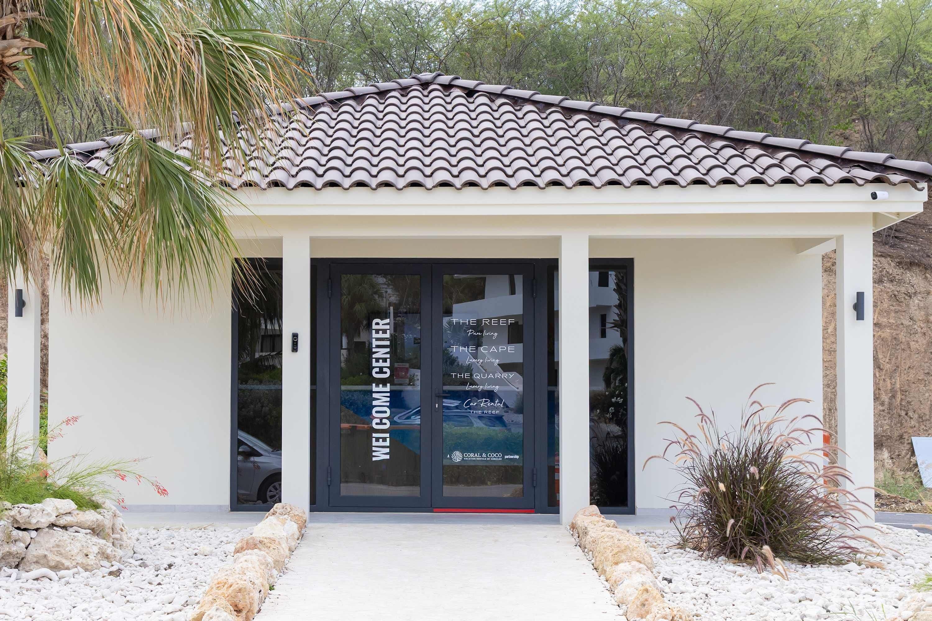 A building with a tiled roof and a glass door with 'WELCOME CENTER' signage.
