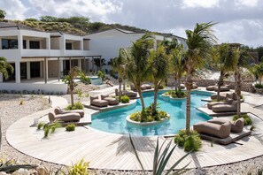 A modern resort with a central pool, outdoor seating, and a multi-story building. - The Reef Superior Penthouse With Ocean View (Sint Michiel)