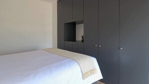 A bedroom with a bed, a dark wardrobe, and a small mirror. - w Sunlit 1BR in the Heart of San Isidro (Lima)