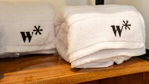 Due asciugamani bianchi con ricamate le lettere 'W' e asterischi su un supporto in legno.
