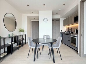 Eine moderne Küche mit Einbauofen und Essbereich mit rundem Tisch und grauen Stühlen.