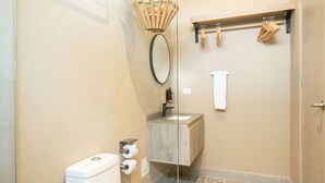 A bathroom with a toilet, a sink, a mirror, and a shower area. - w Flawless Loft in the Heart of Bocagrande (Cartagena)
