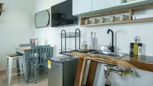 A compact kitchen with a sink, a microwave, a wooden table, and a chair. - w Pleasant Loft in the Heart of Bocagrande (Cartagena)