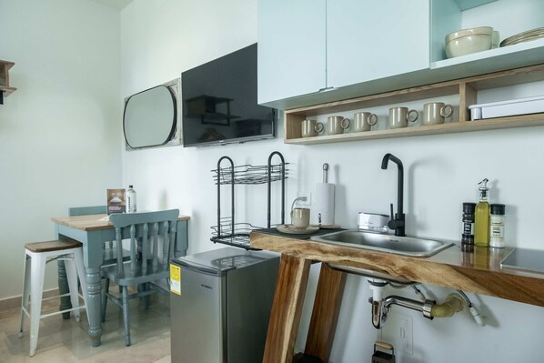 A compact kitchen with a sink, a microwave, a wooden table, and a chair. - w Pleasant Loft in the Heart of Bocagrande (Cartagena)