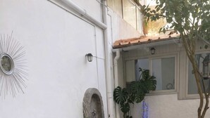 A patio area with a table and chairs, a potted plant, and a decorative wall piece. - Athens Cozy Nest - Prime Central Location (Athens)