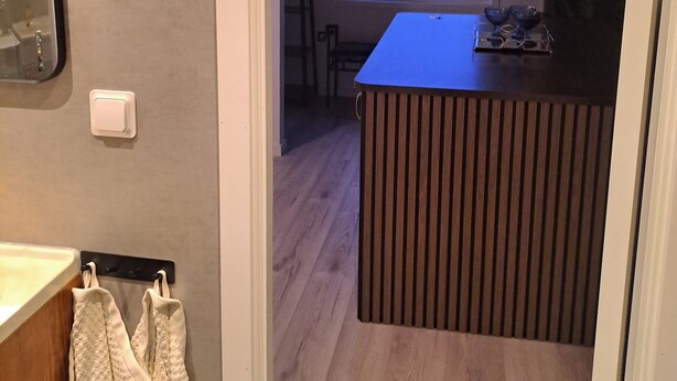 Een moderne keuken met een houten aanrecht, een raam met uitzicht naar buiten, en een klein eiland met een ingebouwde gootsteen.