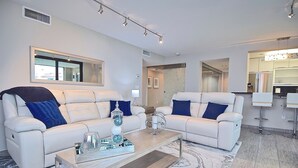 A modern living room with two white sofas, a coffee table, and a large mirror. - New Listing! Beachfront Luxury at Tortuga – Indoor/Outdoor Pool - 3 BDRM (Siesta Key)