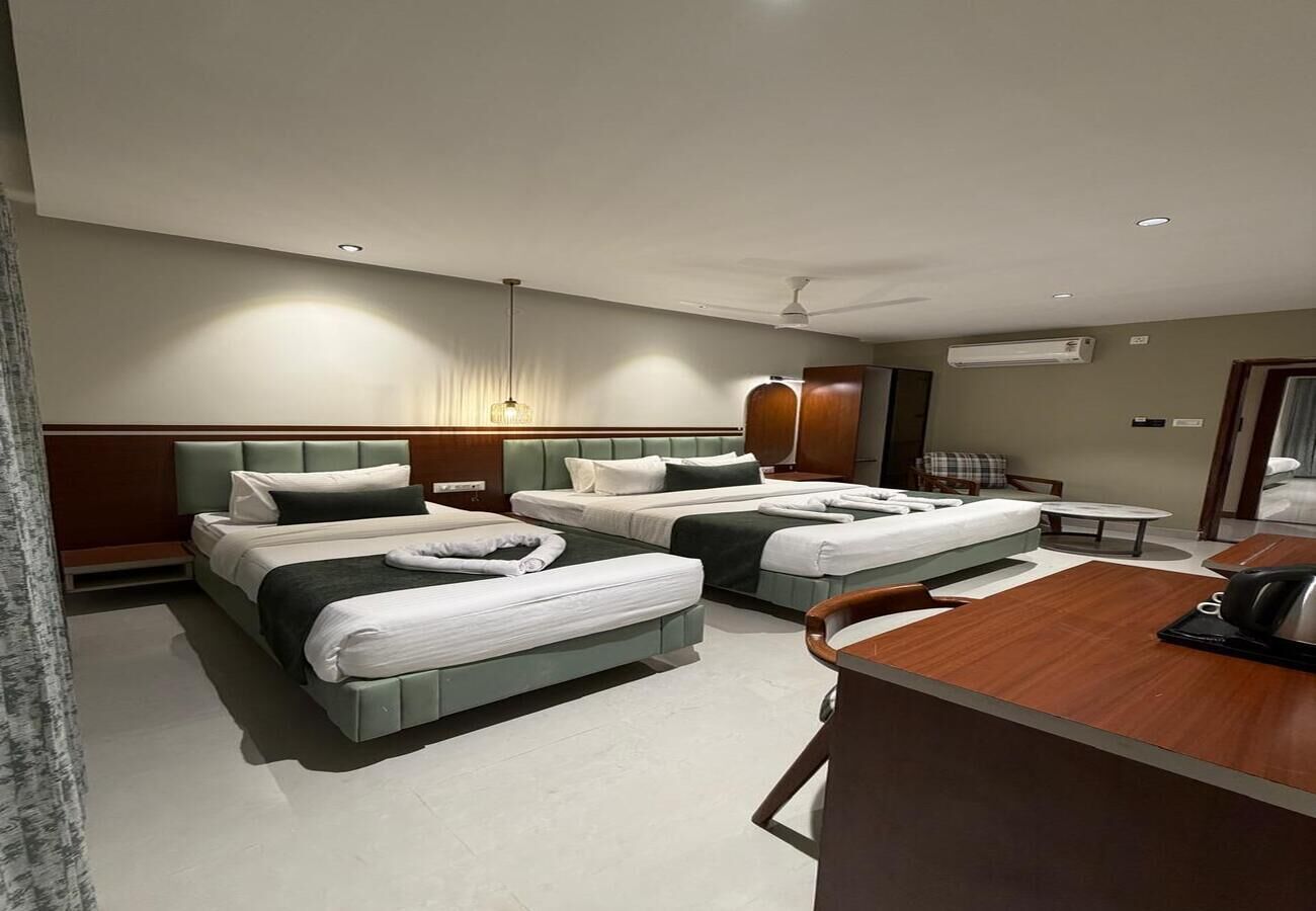 Habitación de hotel con tres camas, un escritorio y una silla.