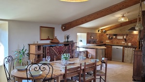 Een landelijke keuken met houten balken, een eethoek met een ronde tafel en stoelen, en een geïntegreerde vaatwasser.