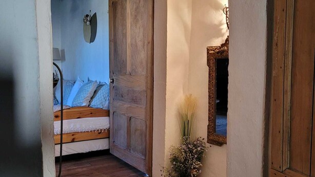 Een rustieke trap die leidt naar een slaapkamer met een houten deur en een spiegel aan de muur.