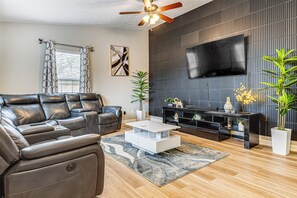 A modern living room with a leather sofa, a white coffee table, and a black entertainment unit. - 9 Mi to Dtwn Indy: Suburban Group Retreat w/ Yard (Indianapolis)
