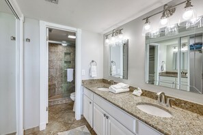 A bathroom with a granite countertop, two sinks, a large mirror, and a shower area. - 3BR Beachfront Condo w/ Pools & Balcony (South Padre Island)