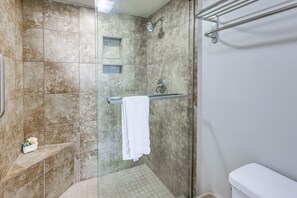 A bathroom with a glass shower enclosure, a white towel hanging on a rack, and a toilet. - 3BR Beachfront Condo w/ Pools & Balcony (South Padre Island)