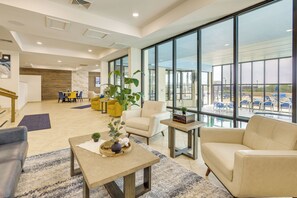 A spacious lobby with a seating area, a coffee table, and large windows offering a view of the parking lot. - 3BR Beachfront Condo w/ Pools & Balcony (South Padre Island)