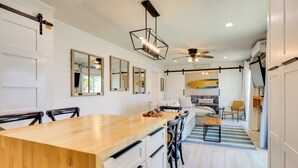 Una cocina moderna con una isla de madera, armarios blancos y un ventilador de techo.