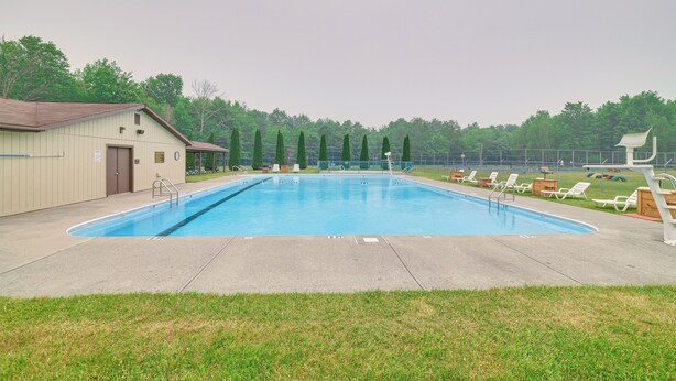 A rectangular swimming pool with a ladder on one side, surrounded by a grassy area and a fence. - Cozy Lake Wallenpaupack Cabin w/ Community Perks (Lake Ariel)