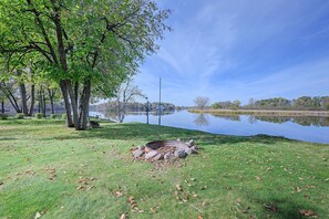A lakeside park with trees, a bench, and a metal fire pit. - Waterfront Petenwell Lake Home w/ Private Dock (Nekoosa)