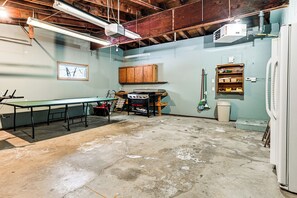 A basement with a ping pong table, a projector, and a refrigerator. - Waterfront Petenwell Lake Home w/ Private Dock (Nekoosa)