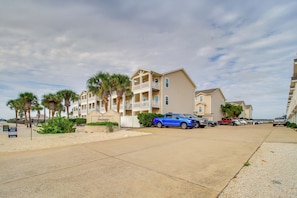 A beachfront hotel with multiple-story buildings, a parking area, and palm trees. - Walk to Beach & Dining: Corpus Christi Townhome (Corpus Christi)
