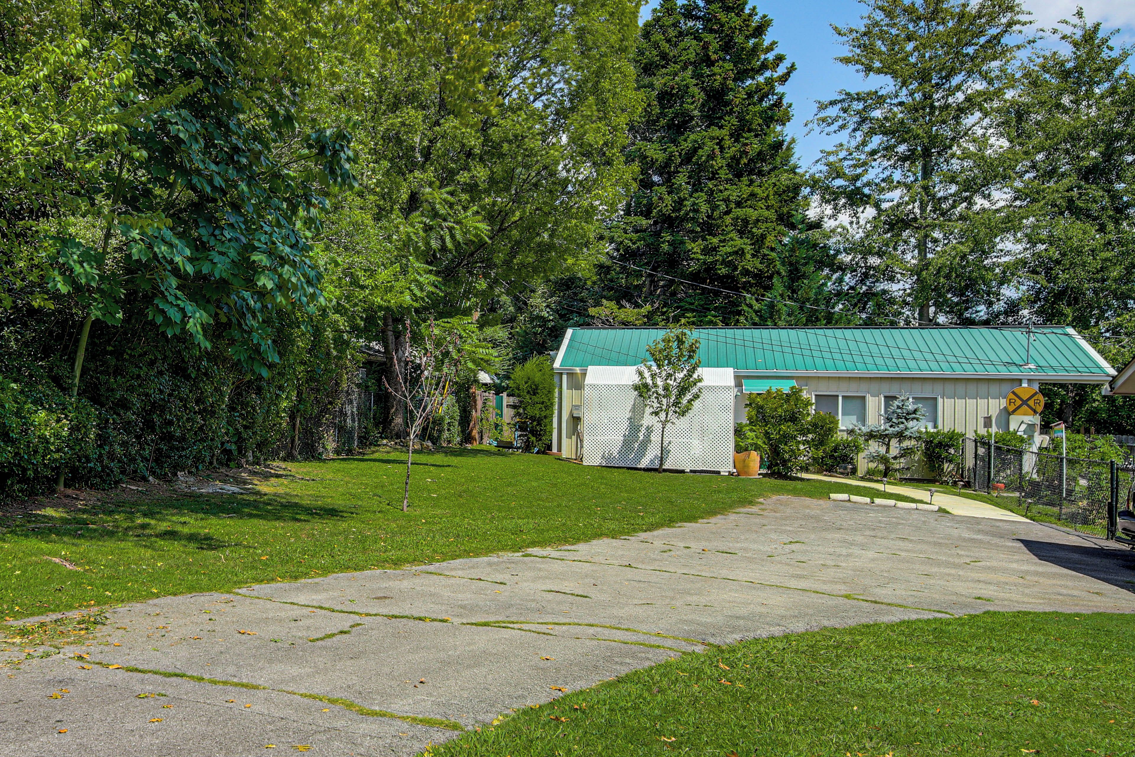 Una propiedad residencial con una casa de techo verde, un patio cercado y cielo despejado.
