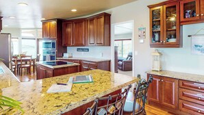 A spacious kitchen with granite countertops, wooden cabinets, and a central island.