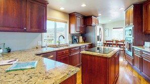 A spacious kitchen with wooden cabinets, granite countertops, and a large island.
