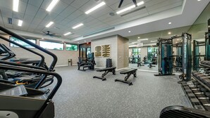 Uma academia com esteiras, bancos de musculação e diversos aparelhos de exercício.