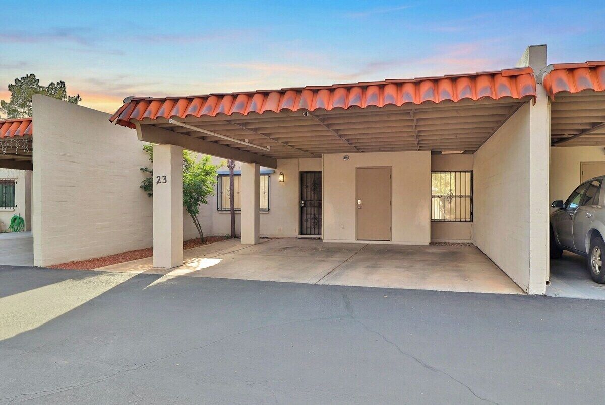 A single-story building with a covered parking area, numbered 23, and a car parked inside.