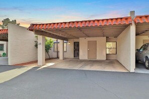 Un bâtiment d’un seul étage doté d’un espace de stationnement couvert, portant le numéro 23, et où une voiture est garée à l’intérieur.