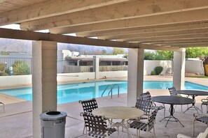 Un espace extérieur aménagé en terrasse, avec une piscine, des sièges et une vue sur un bâtiment en arrière-plan.