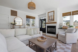 A living room with a sofa, armchair, coffee table, fireplace, and large windows with blinds. - RENOVATED, DOG FRIENDLY 3 BEDROOM COTTAGE IN REHOBOTH BEACH (Rehoboth Beach)