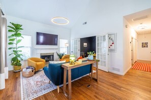 A modern living room with a fireplace, a television, and a dining area with a table and chairs. - Walk to BeltLine | 3 Miles to World Cup Stadium (Atlanta)