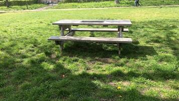 A picnic table in a grassy park area with buildings in the background.