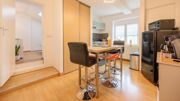 Una cocina moderna con comedor, suelo de madera, electrodomésticos de acero inoxidable y una puerta corredera.