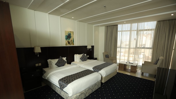A hotel room with two beds, a large window with curtains, a desk, and a chair. - Layale Lamar Hotel (Jeddah)