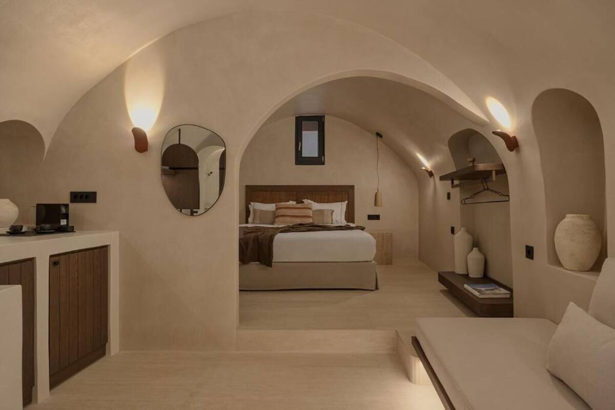 A bedroom with a bed, bedside tables, a mirror, and a small window.