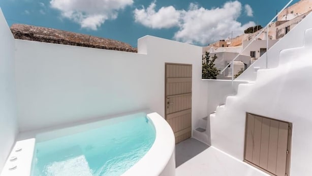 Un'area spa moderna all'aperto con vasca idromassaggio, pareti bianche e una scala che conduce a un terrazzo.