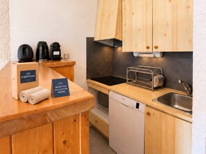 A modern kitchen with wooden cabinets, a built-in oven, a coffee machine, and a dish rack. - Apartment near slopes with balcony, valley view (Méribel)