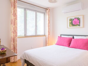 Un dormitorio con cama, escritorio y ventana con cortinas.
