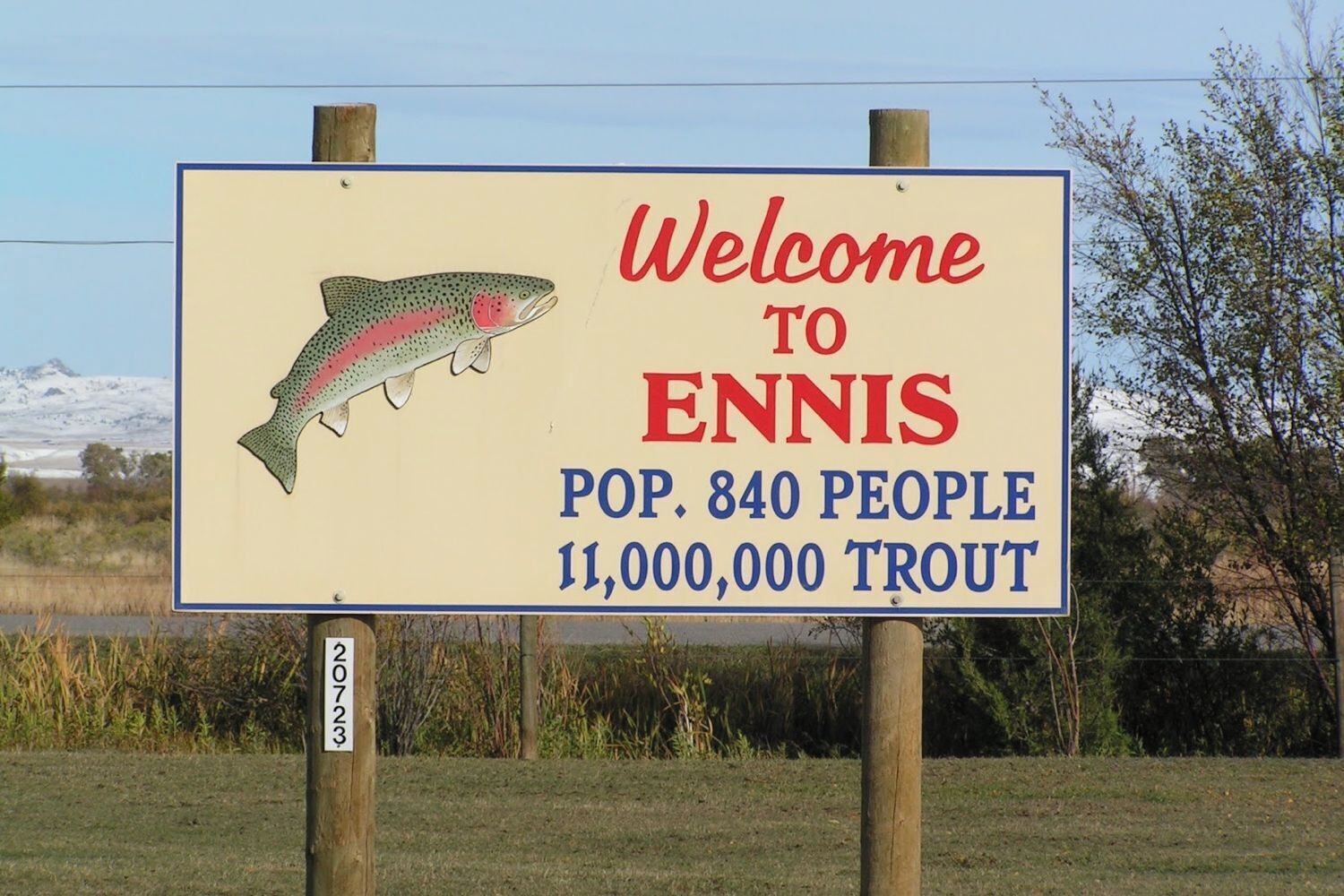 A welcome sign for Ennis with a trout illustration, population of 840 people, and 11 million trout.