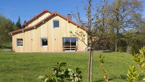 Ein zweistöckiges Holzhaus mit rotem Dach, einer Veranda und einem großen Fenster.